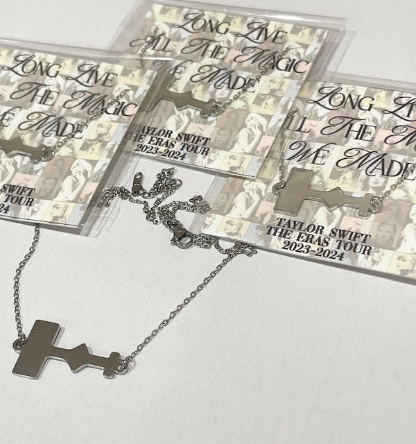 Stainless steel necklace shaped like the Eras Tour stage shown on a card that says “Long Live All the Magic We Made – Taylor Swift The Eras Tour 2023–2024.”