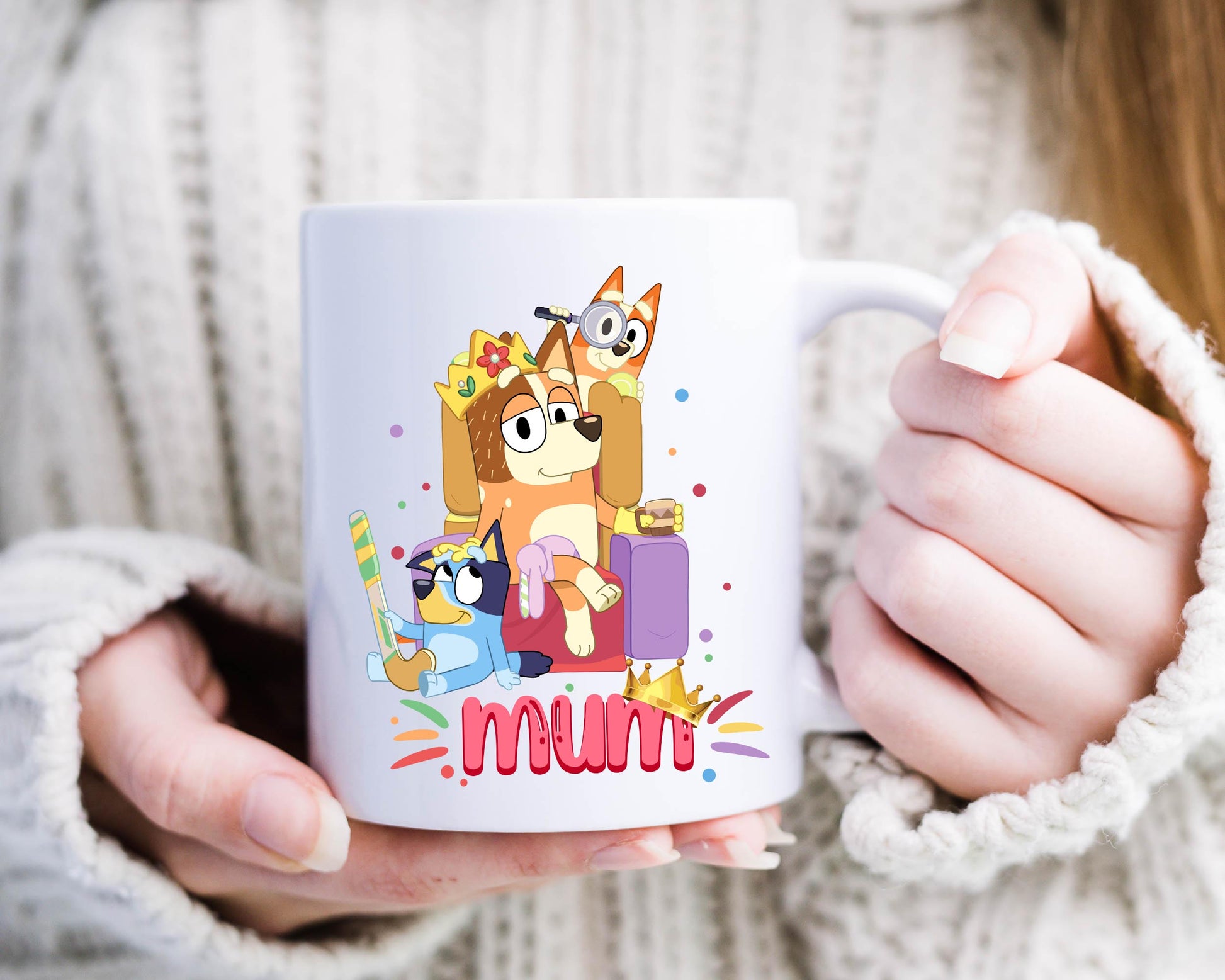 Woman holding a white ceramic mug with cartoon characters inspired by Bluey, featuring Mum, Bluey, and Bingo, with the word “mum” in colorful text below.