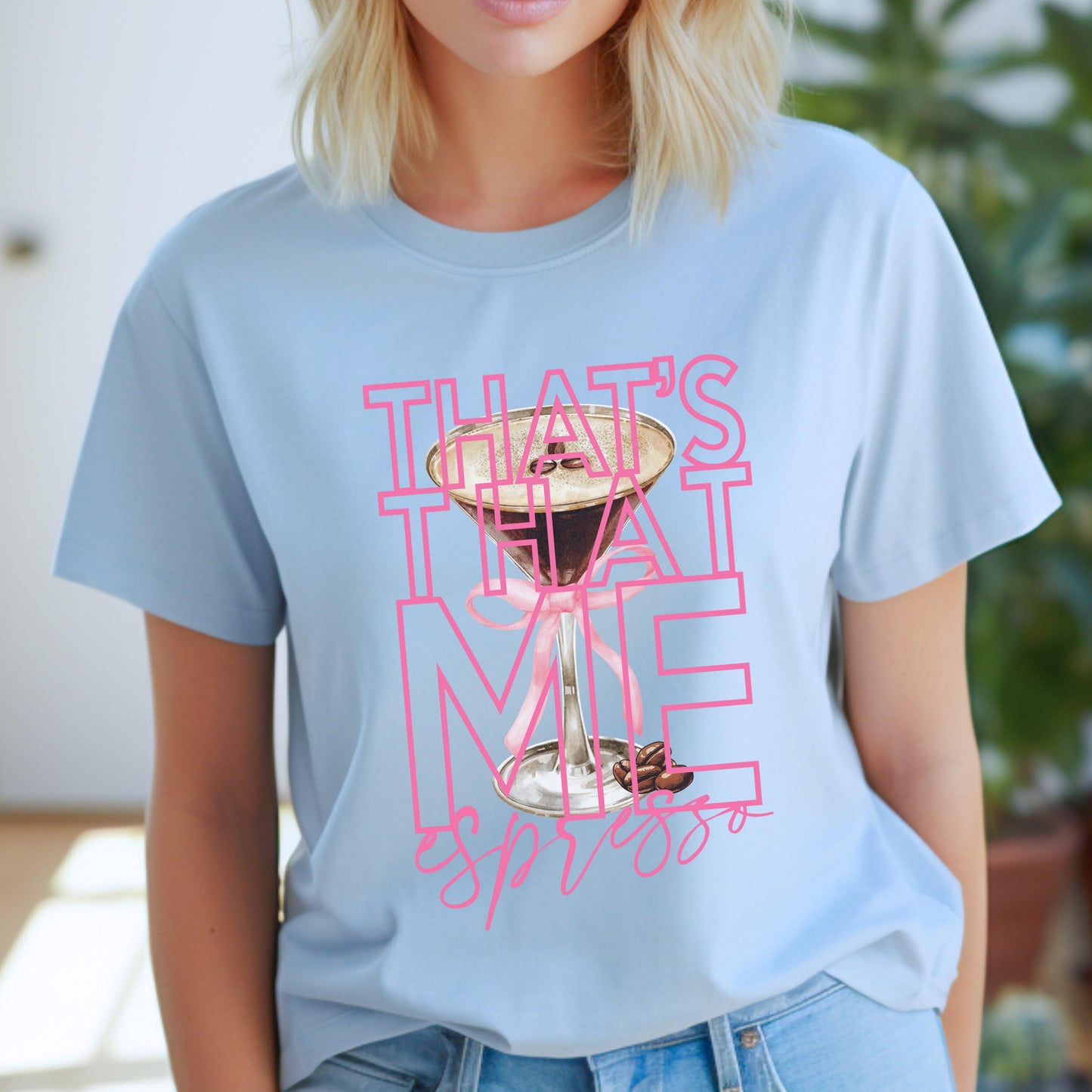 Woman wearing a light blue graphic t-shirt with bold pink text that reads "That’s That Me Espresso" featuring an espresso martini glass; inspired by Sabrina Carpenter’s hit song.