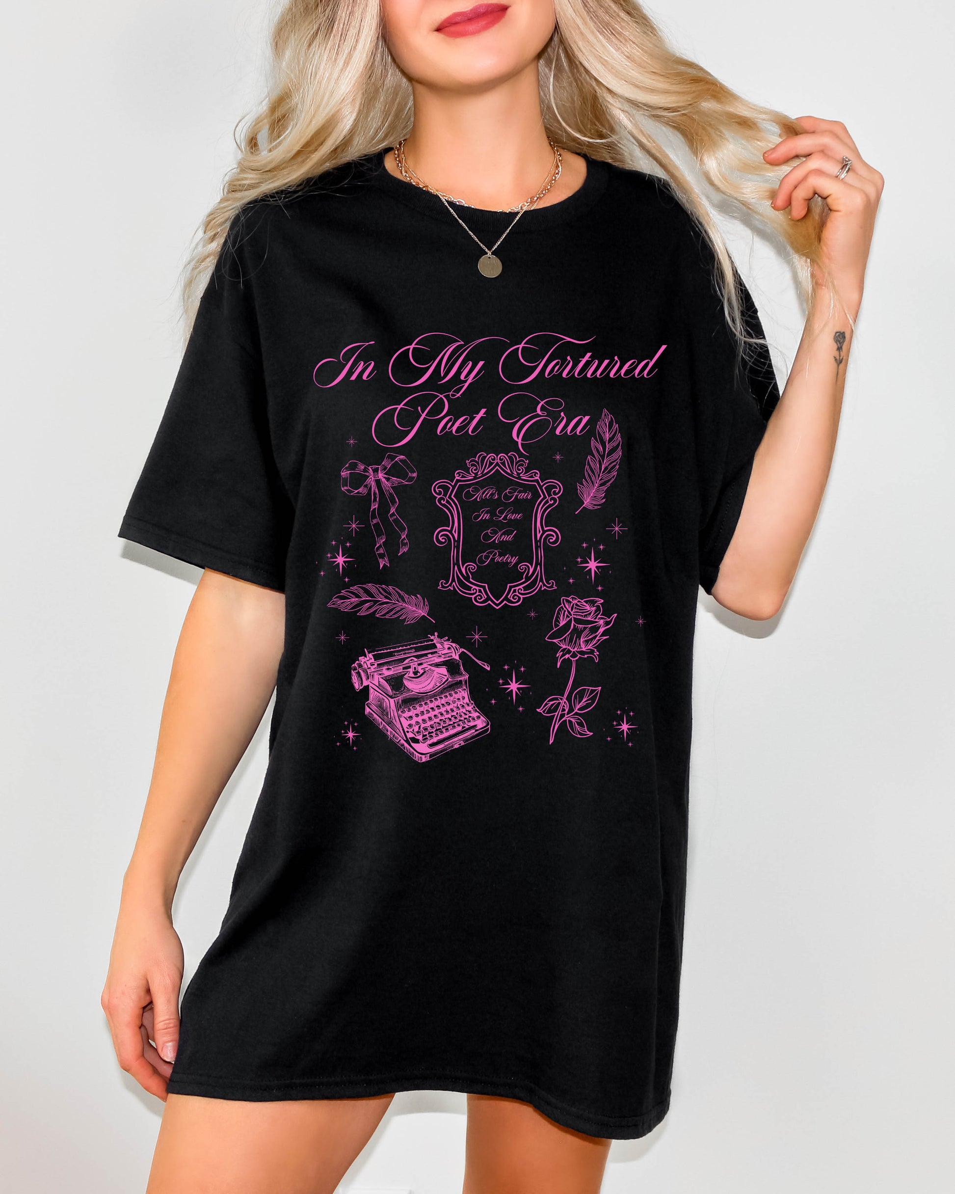 Woman wearing a black t-shirt dress that reads “In My Tortured Poet Era” with gothic illustrations including a typewriter, quill, rose, and ornate frame in pink ink.