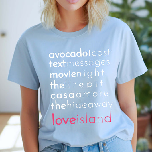 Woman wearing a pink t-shirt with Love Island-inspired phrases like “avocado toast,” “the fire pit,” and “casa amor,” holding pink balloons on a beachside deck.