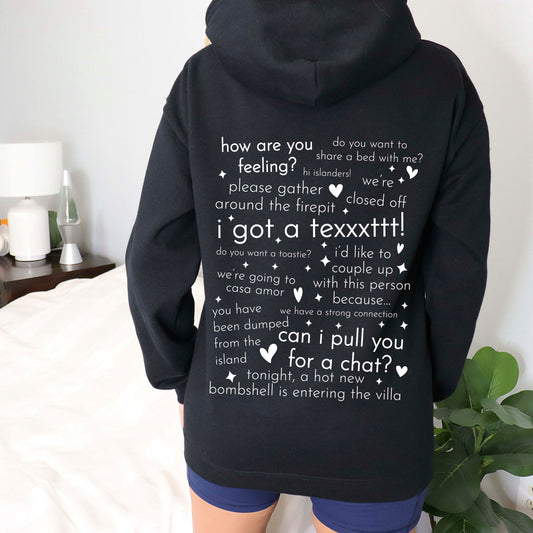 Black zip-up hoodie featuring famous Love Island phrases like "I got a text!" and "Can I pull you for a chat?" in white text with hearts and sparkle accents.