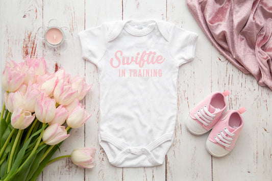 Swiftie in Training baby onesie styled with tulips and pink sneakers