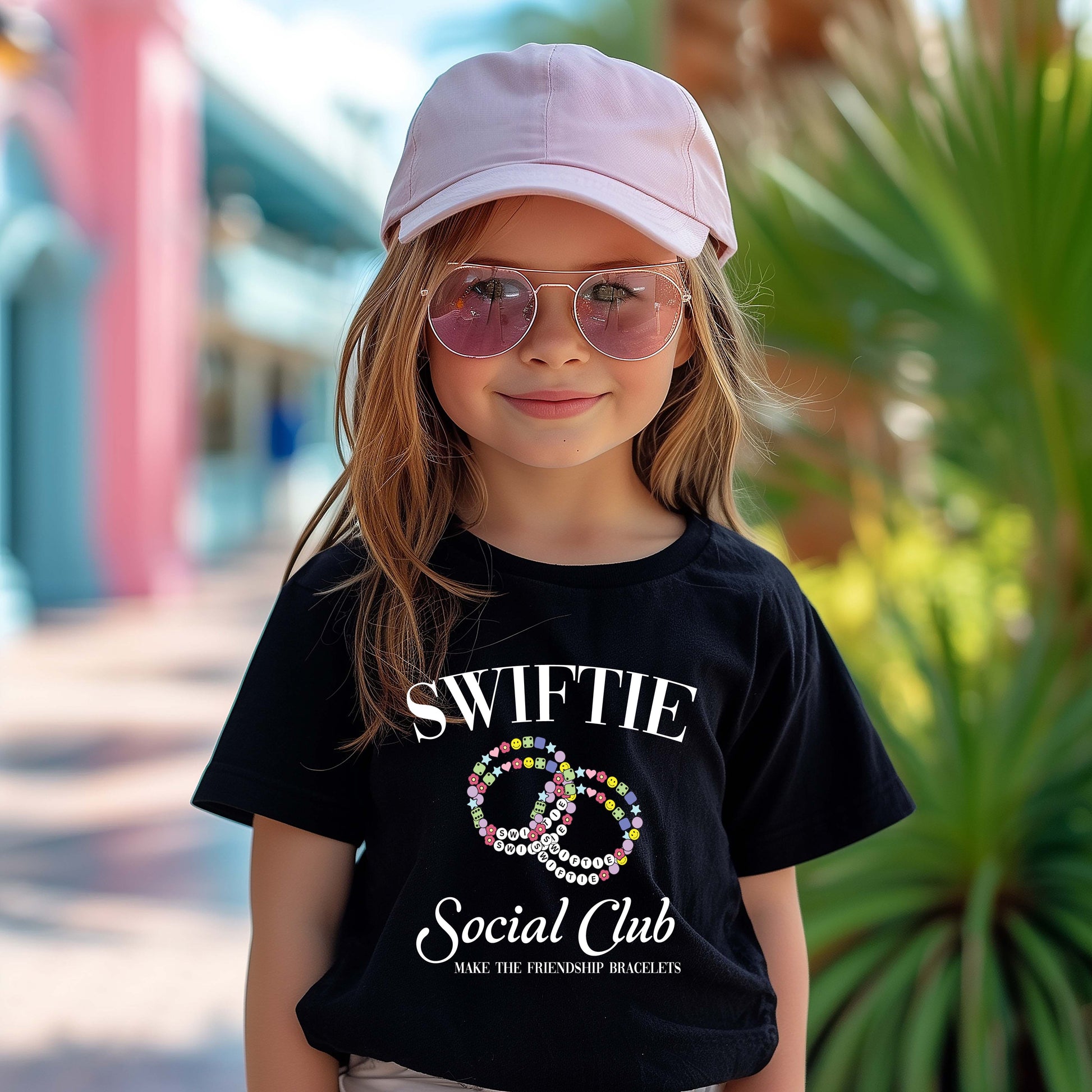 Woman wearing a black oversized t-shirt dress with a colorful friendship bracelet graphic and “Swiftie Social Club” text